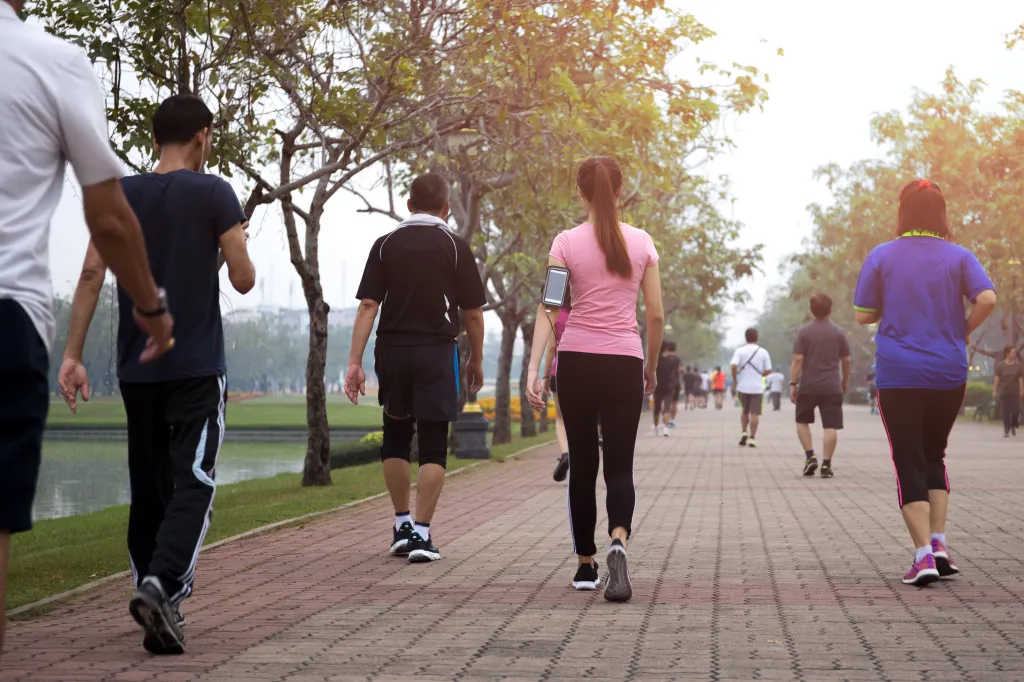 A group of people exercise walking in a park in the morning.