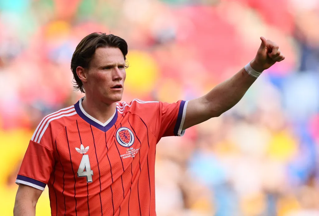 Scotland's Scott McTominay in a red jersey, raising his arm on a colorful field.