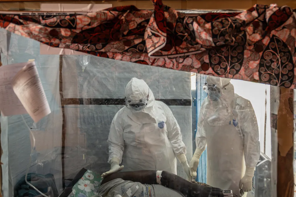 Health workers in protective suits tend to an Ebola patient in a treatment center.