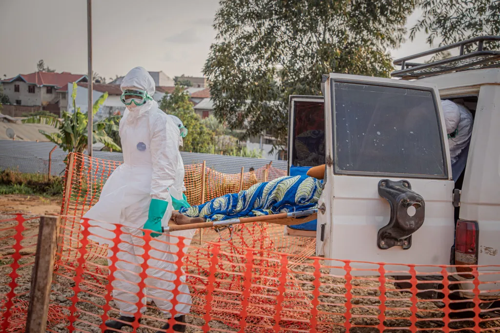 Healthcare workers in full protective gear carry a patient suffering from Ebola from an ambulance.