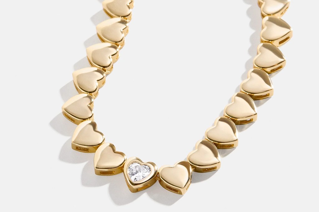 Gold heart-shaped necklace with one heart containing a diamond.