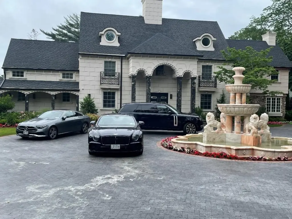 House of Nduka Lewis Ekpenyong with three luxury cars and a fountain in the driveway.
