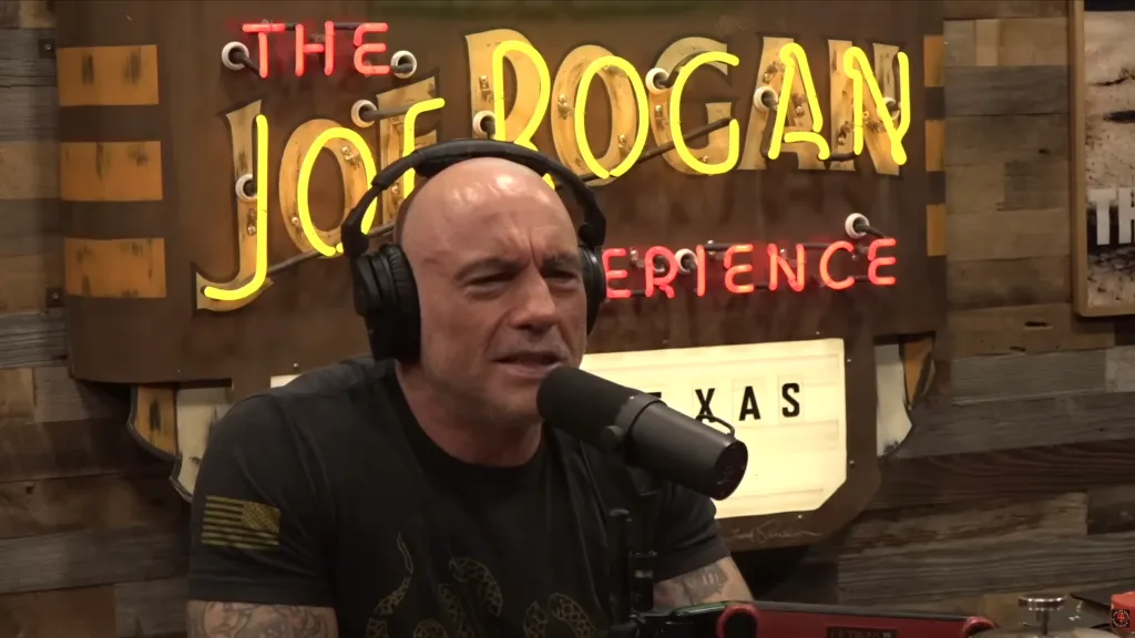Joe Rogan wearing headphones and speaking into a microphone.