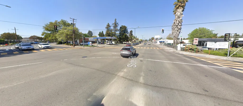 A wide shot of Soto Road with a gas station, a brake repair shop, and cars at a busy intersection.