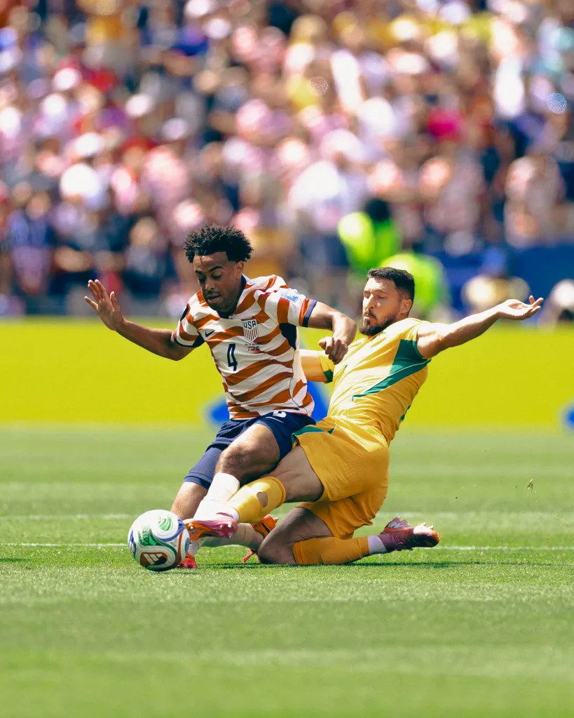 Tyler Adams #4 of the United States is tackled by Mathew Leckie #7 of Australia during the FIFA World Cup 2026 Group D match between USA and Australia at Seattle Stadium on June 19, 2026 in Seattle, Washington. 