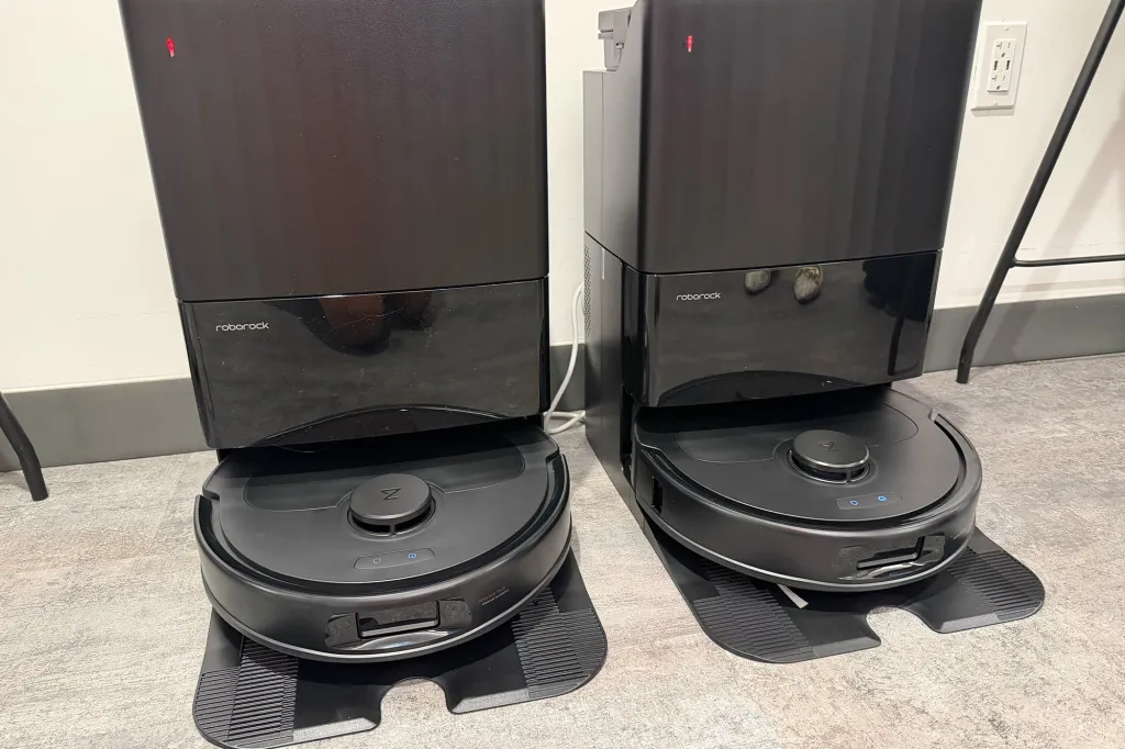 Two black Roborock robot vacuums charging at their docking stations.