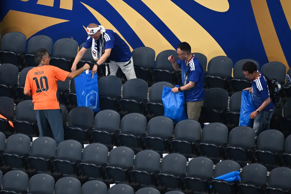 Japanese fans clean up trash in the stadium following the World Cup Group F soccer match.