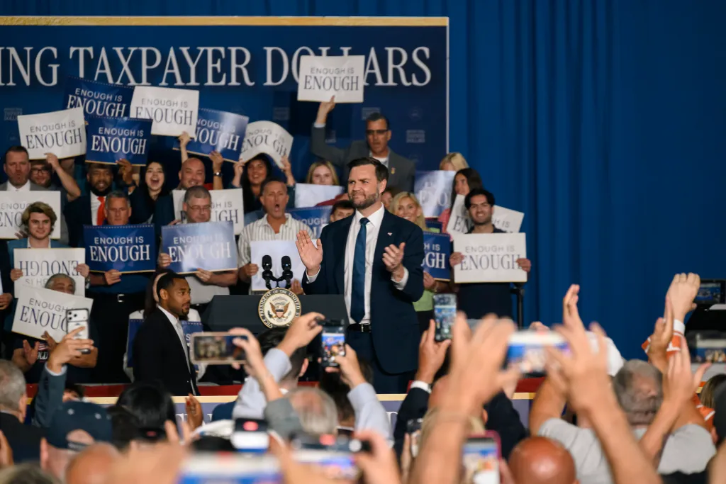 JD Vance addresses a crowd holding signs that say "Enough is Enough."