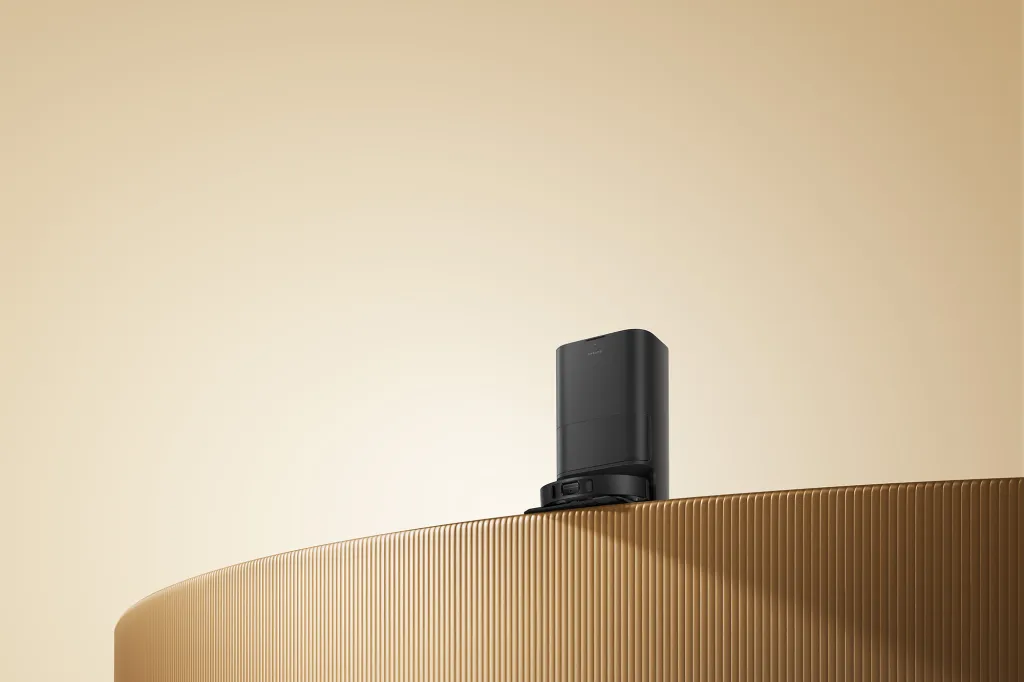 Black robotic vacuum cleaner on a ridged brown surface.
