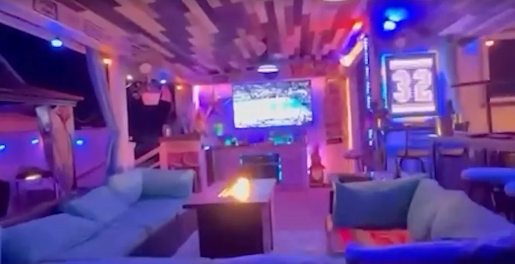 A house decked out for the NBA finals, featuring a large screen showing a game, multiple couches, and mood lighting.