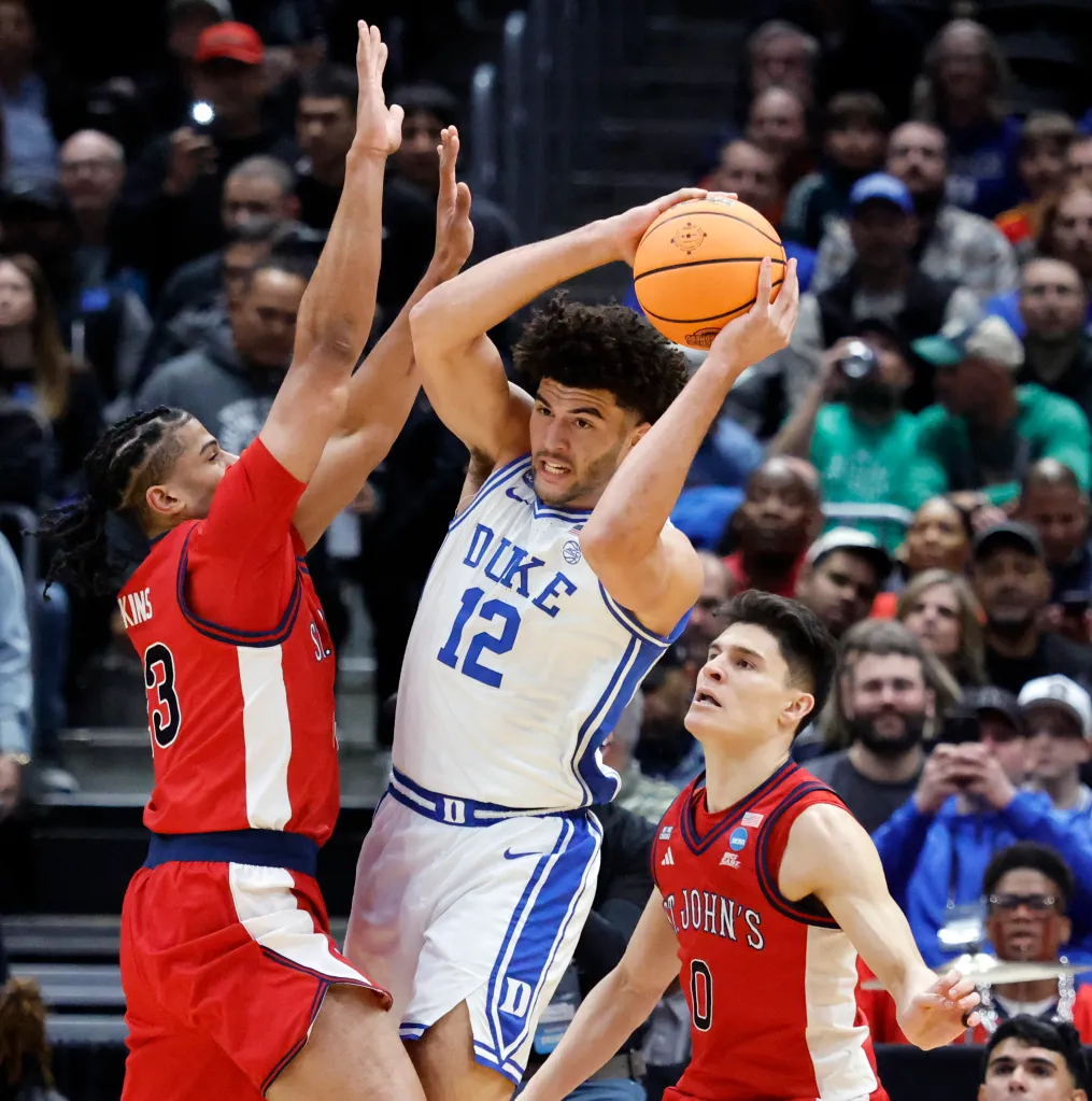 Duke Blue Devils forward Cameron Boozer (C) looks to pass past a defending St. John's Red Storm forward Bryce Hopkins (L) and teammate St. John's Red Storm guard Dylan Darling (R).