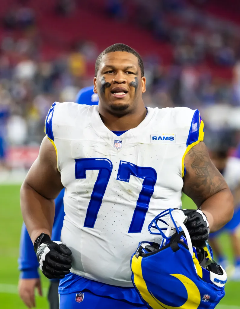 Los Angeles Rams offensive lineman Alaric Jackson (77) wearing eye black and holding his helmet.