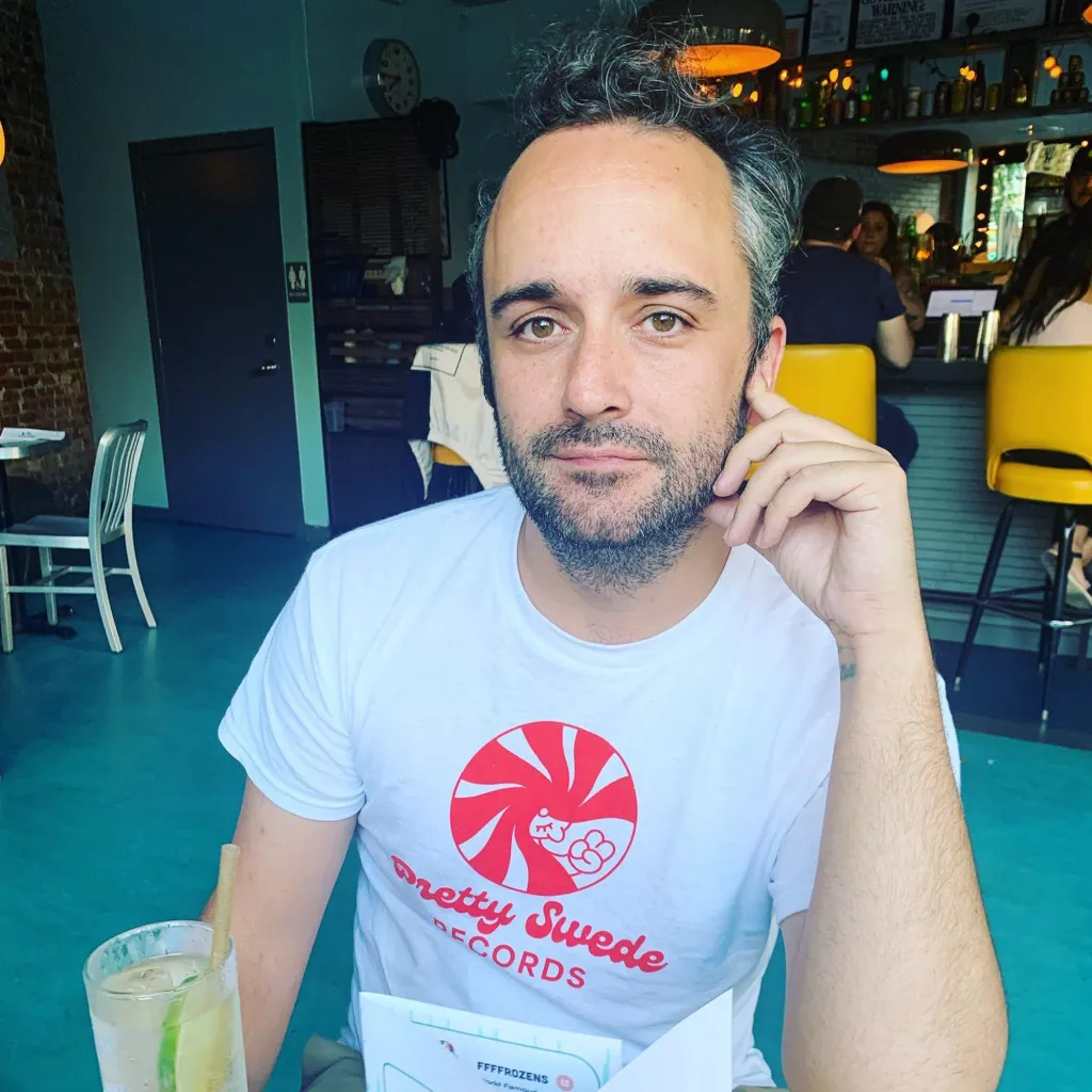 Caleb Willdee, an executive producer for Love Island USA, wearing a white t-shirt with a red "Pretty Swede Records" logo.