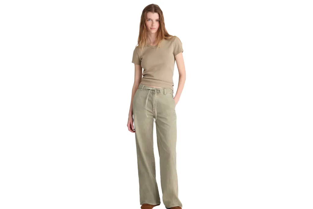 A woman wears a beige short-sleeved t-shirt and olive-green pants with a drawstring waist.