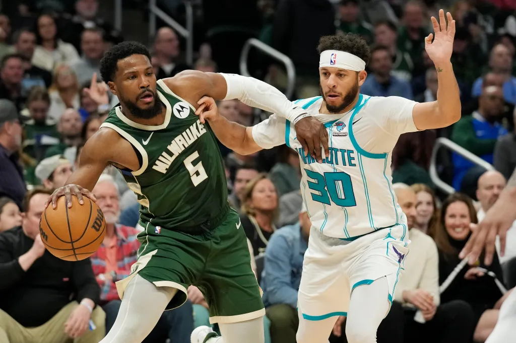 Milwaukee Bucks player, wearing number 5, dribbles the ball while being defended by a Charlotte Hornets player, wearing number 30.
