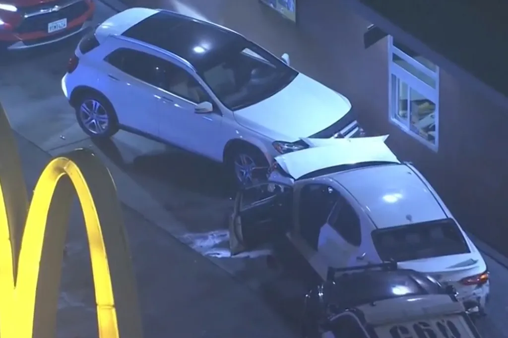 Multiple cars damaged in a crash, including a white SUV and a white car with its hood up, next to a McDonald's sign.