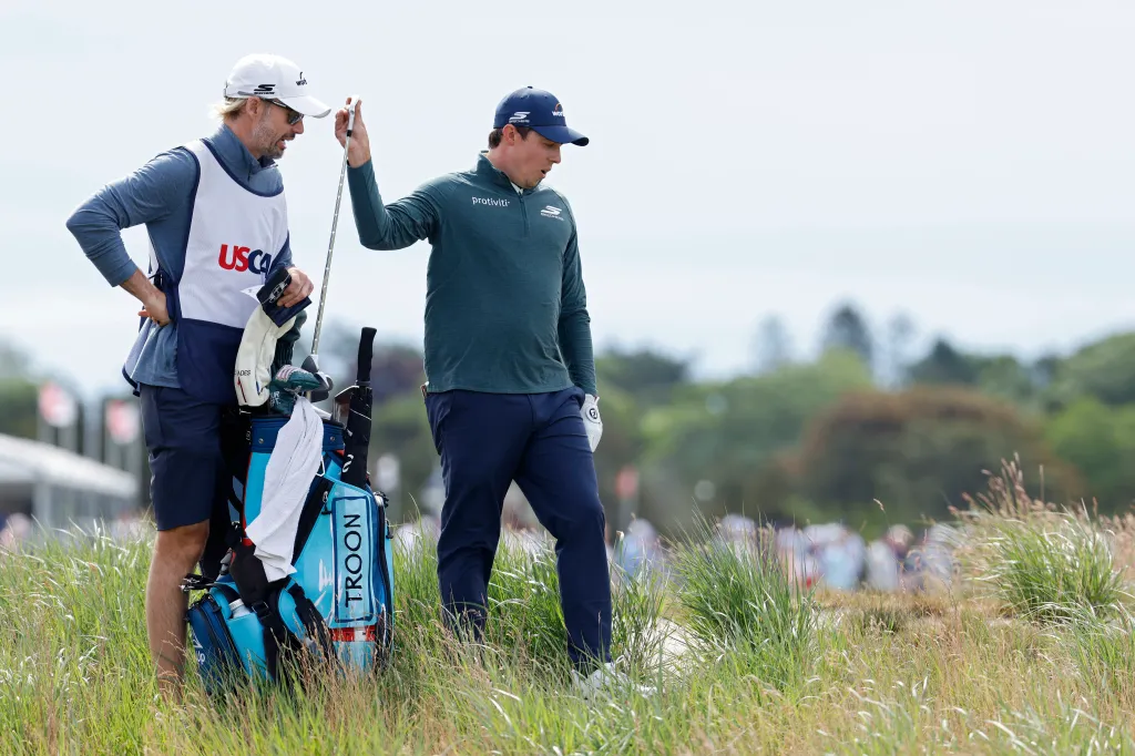 Golfer Matt Fitzpatrick and his caddie discuss club selection on the sixth hole during the 126th U.S. Open.
