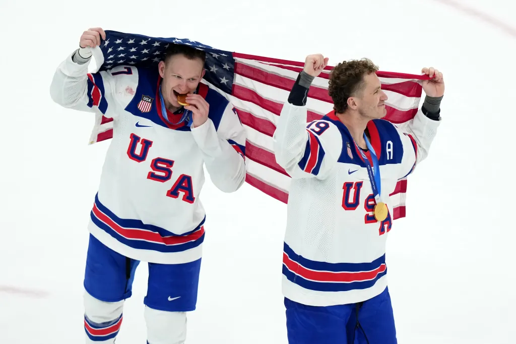 Brady Tkachuk and Matthew Tkachuk celebrating with the US flag and their gold medals.