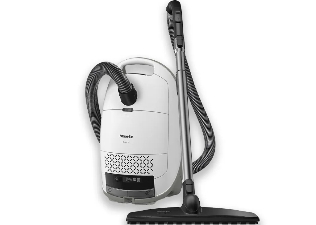 A white Miele canister vacuum cleaner with a black hose and wand.