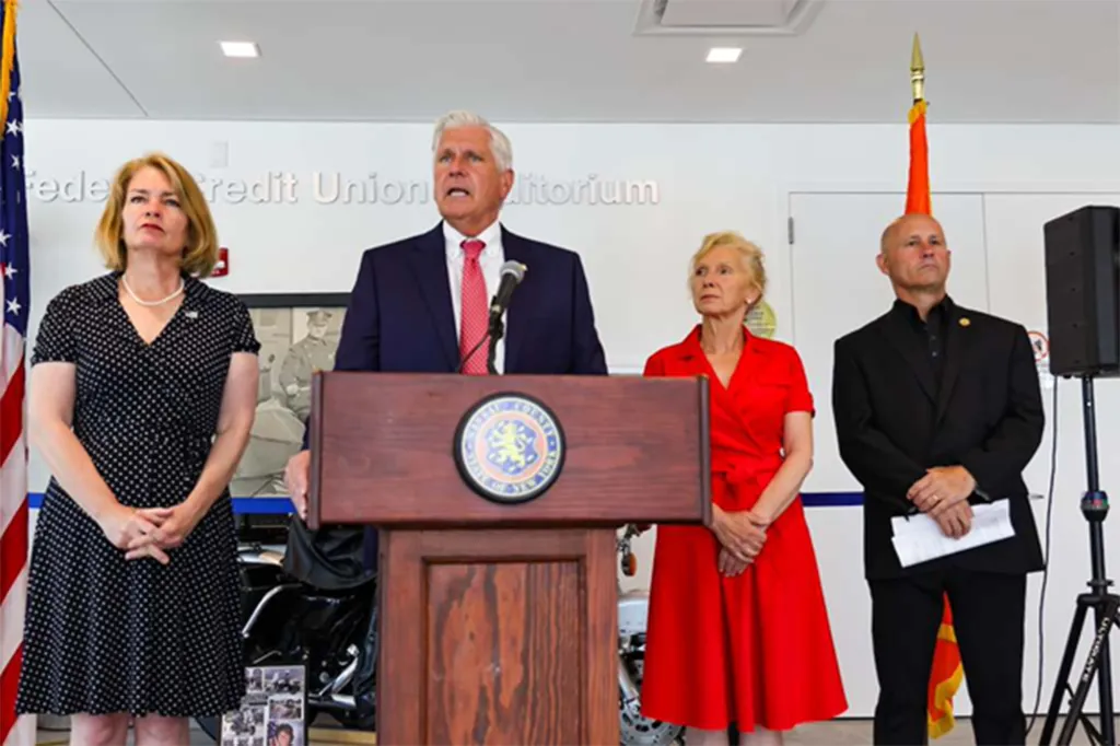 Nassau County Executive Bruce Blakeman speaks at a podium with three other individuals standing behind him.