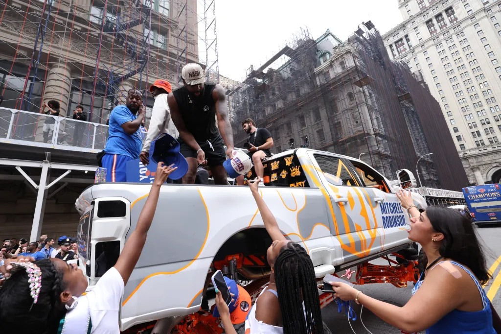 New York Knicks player Mitchell Robinson signs autographs for fans while celebrating the team's NBA championship during a ticker-tape parade down Lower Manhattan's "Canyon of Heroes" on Broadway, Thursday, June 18, 2026 in New York.
