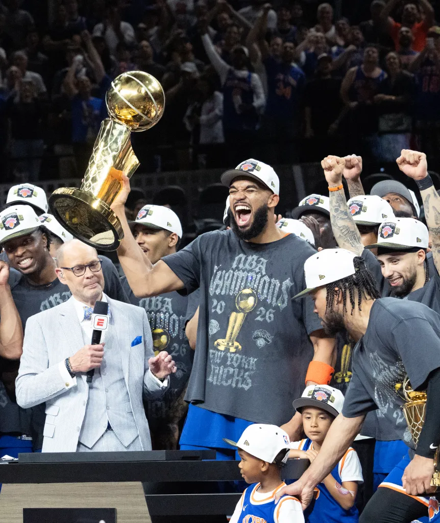 Karl-Anthony Towns (c.) lifts the Larry O'Brien trophy as the Knicks celebrate winning the NBA championship on June 13, 2026.