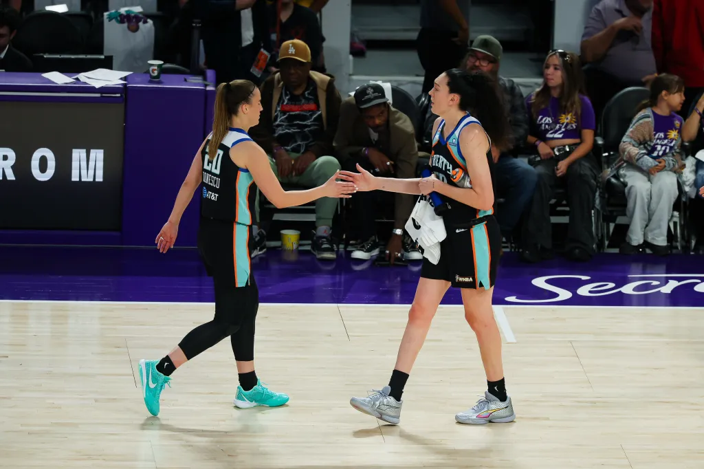 New York Liberty players Sabrina Ionescu and Breanna Stewart high-five each other.