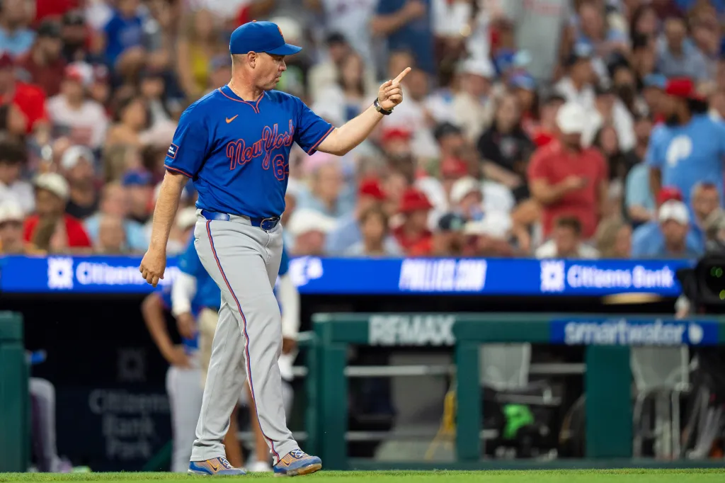 New York Mets manager Carlos Mendoza emerges from the dugout to make a pitching change.
