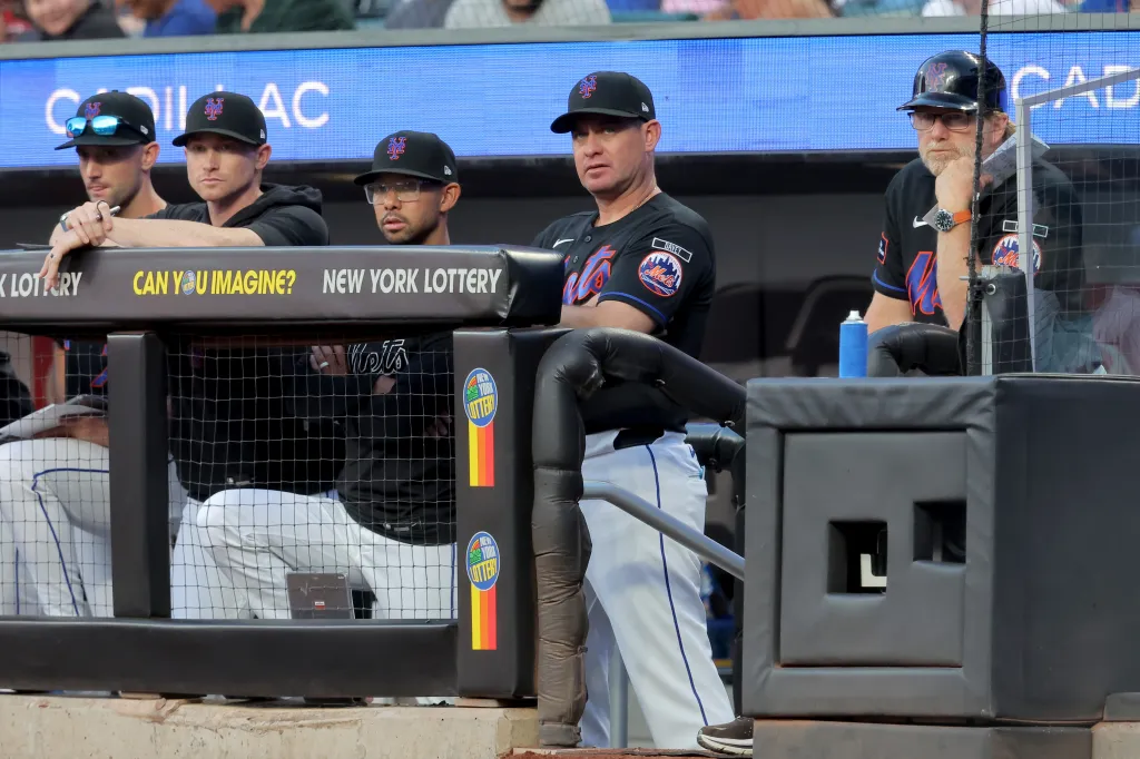 New York Mets manager Carlos Mendoza and other Mets personnel in the dugout.
