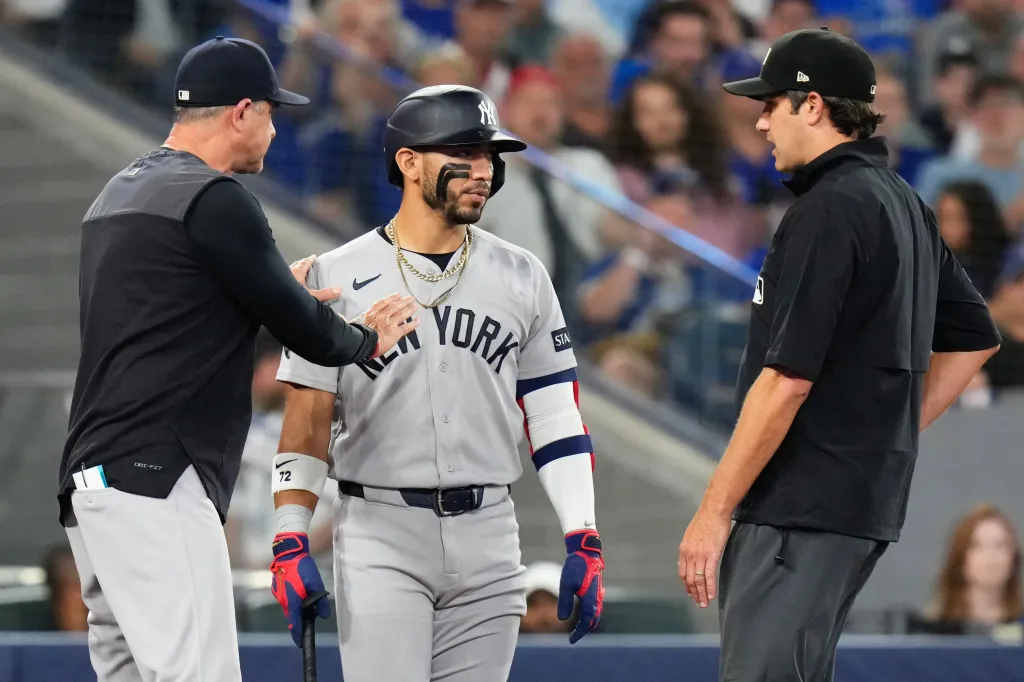 Yankees manager Aaron Boone gestures to player José Caballero, who exchanges views with second base umpire John Tumpane.