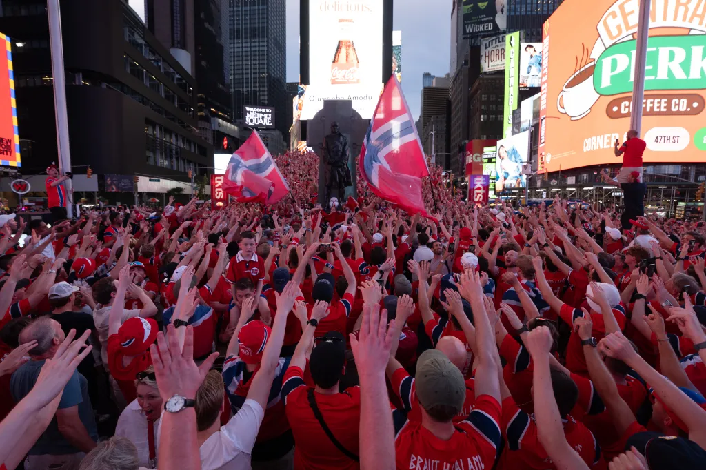 Norwegian national football team supporters with raised hands in Times Square before a World Cup match.