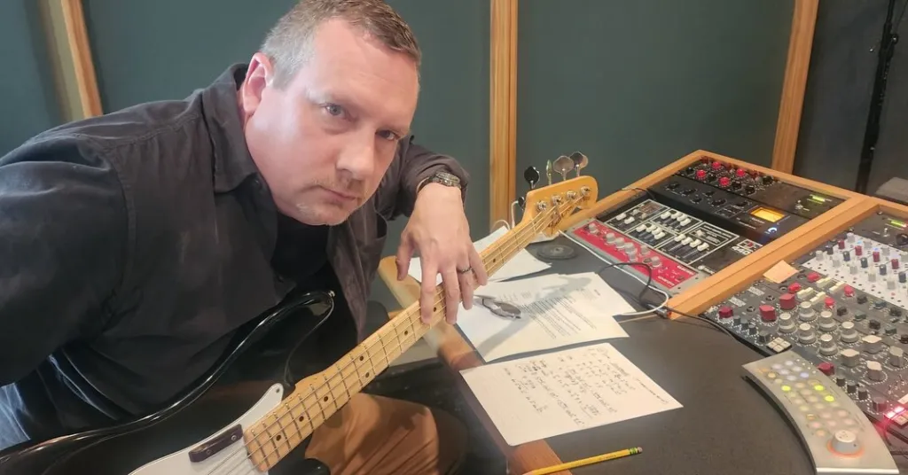 Justin Cary playing bass in a recording studio.