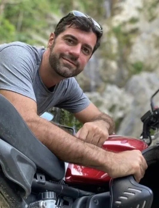 Daniel P. Riva leaning on a motorcycle.