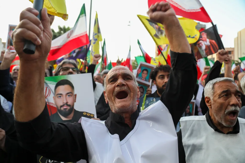 People at Palestine Square in Tehran gather in support of Iranian leadership, holding flags and images of leaders.