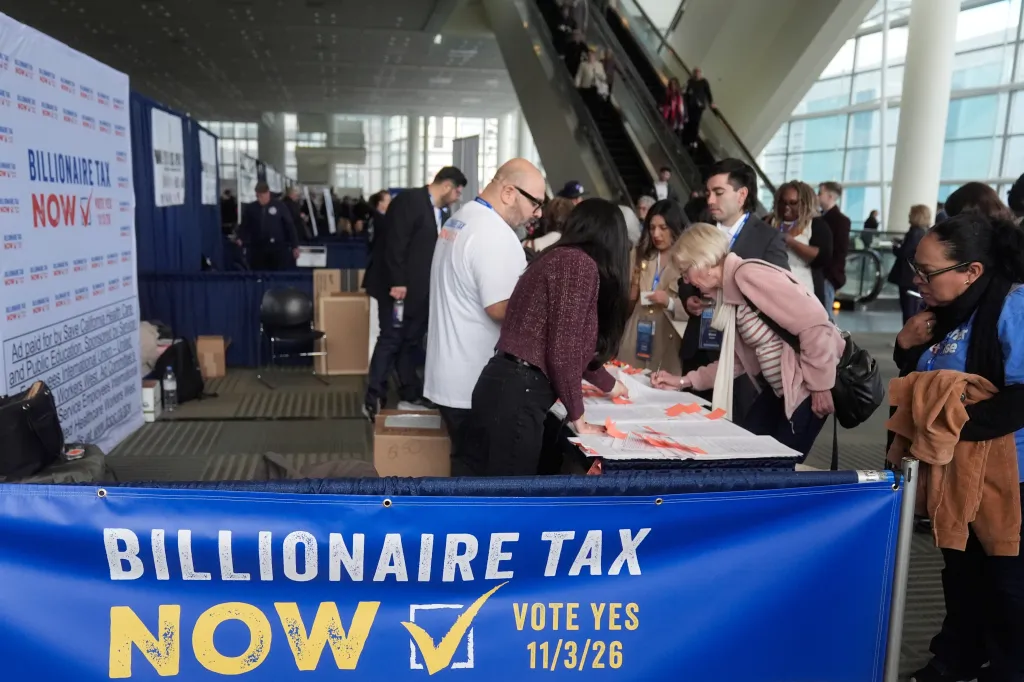 People signing documents at the "Billionaire Tax Now" booth during the California Democratic Convention.