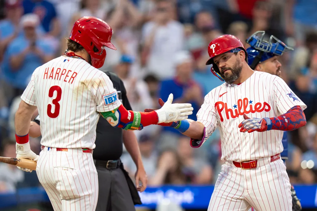 Philadelphia Phillies players Kyle Schwarber and Bryce Harper high-five after Schwarber's home run.