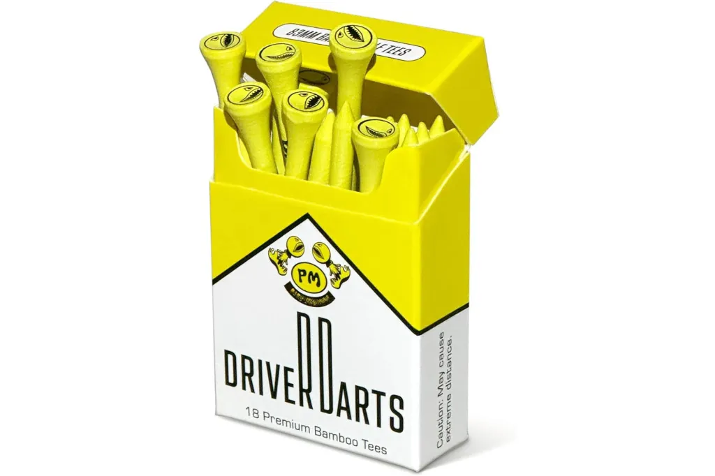 A yellow box of golf tees shaped like a cigarette pack with "DRIVER DARTS" and "18 Premium Bamboo Tees" on the front, showing several yellow golf tees with smiling shark faces on top.