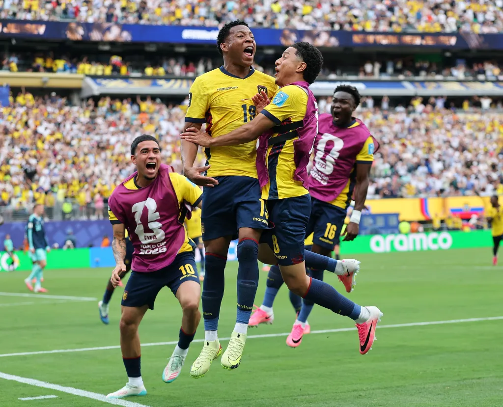 Ecuadorian player Plata (19) celebrates scoring a goal with teammates, jumping and yelling in excitement.