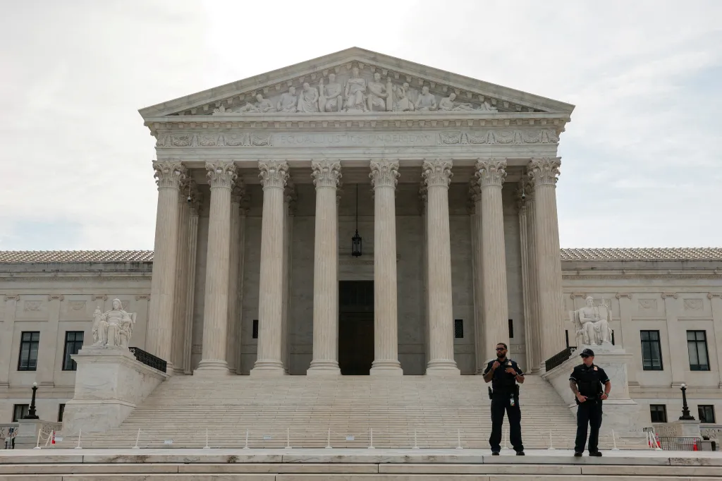 Two police officers stand on the steps of the U.S. Supreme Court building.