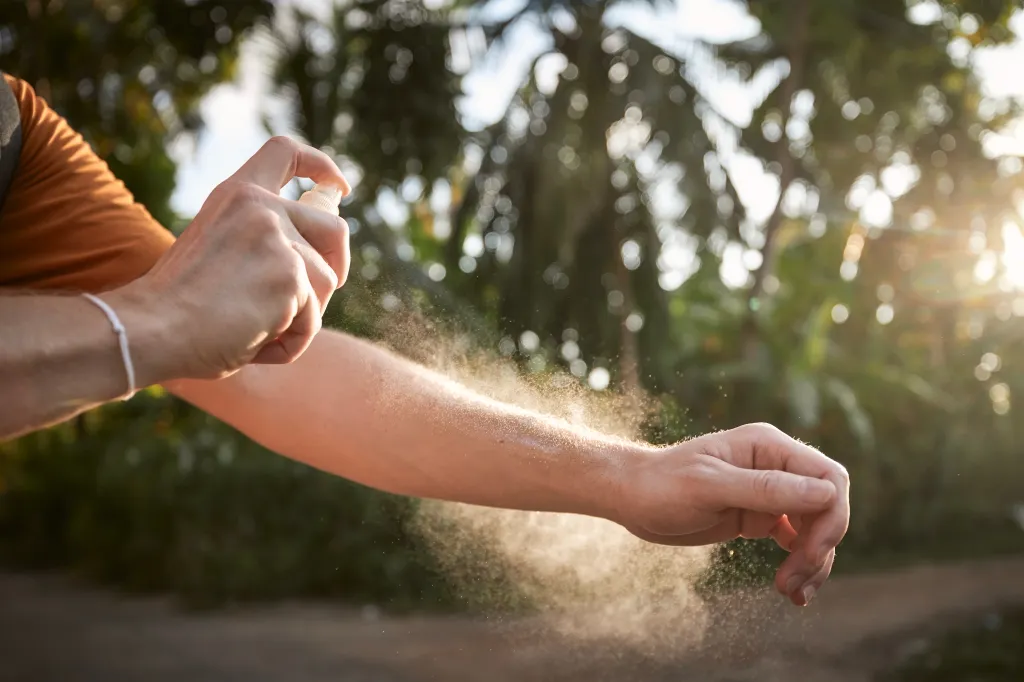 Person spraying insect repellent.