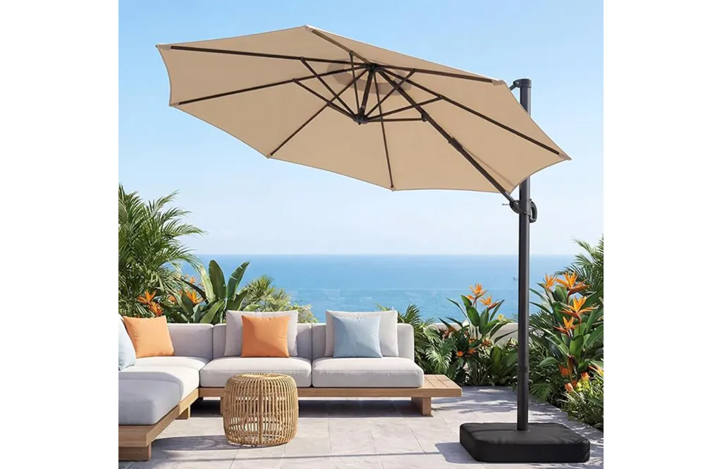 An outdoor umbrella shades a modern patio set on a terrace overlooking the ocean.