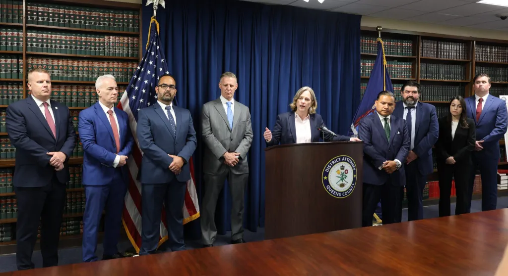 Queens District Attorney Melinda Katz speaking at a podium alongside Governor Kathy Hochul, NYC Police Commissioner Jessica S. Tisch, and several other individuals.