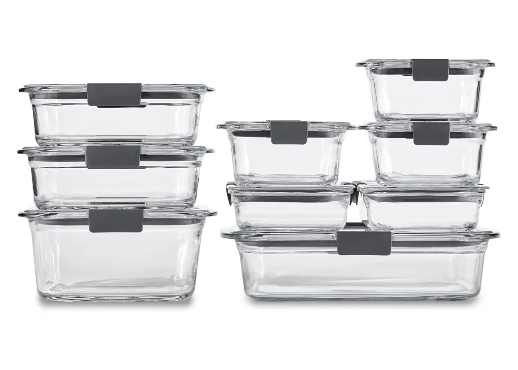An assortment of clear glass Rubbermaid food storage containers with gray lids, stacked and arranged in two groups.