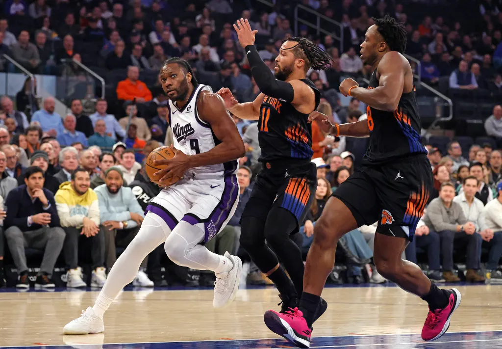 Sacramento Kings player Precious Achiuwa drives to the basket as New York Knicks players Jalen Brunson and OG Anunoby give chase.