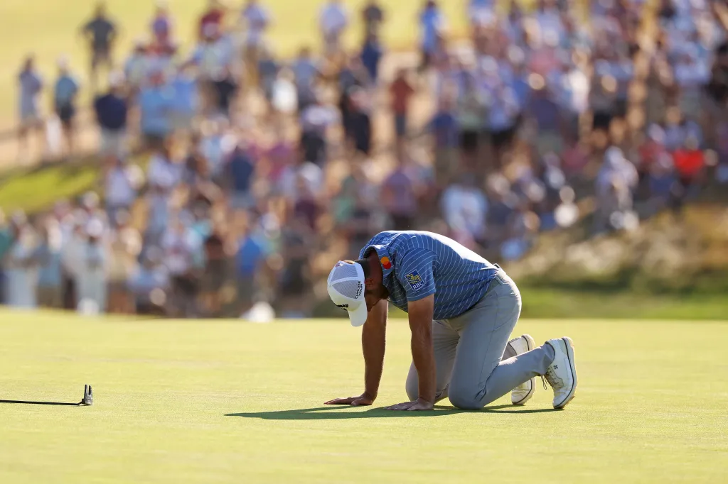 Golfer Sam Burns kneels on a green in disappointment after missing a putt at the U.S. Open.