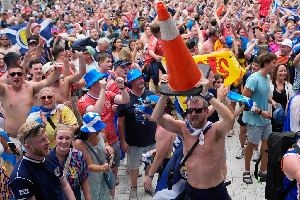 A Scotland soccer fan dances with a traffic cone on his head during a march.