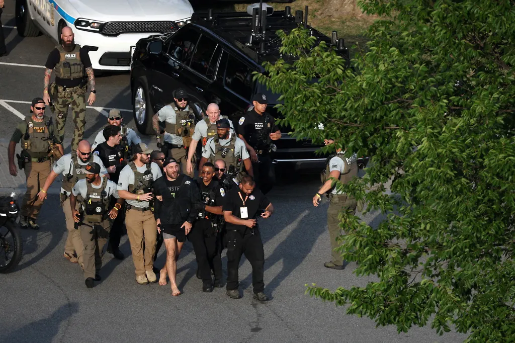 Law enforcement officers escorting a barefoot man away from a White House event.