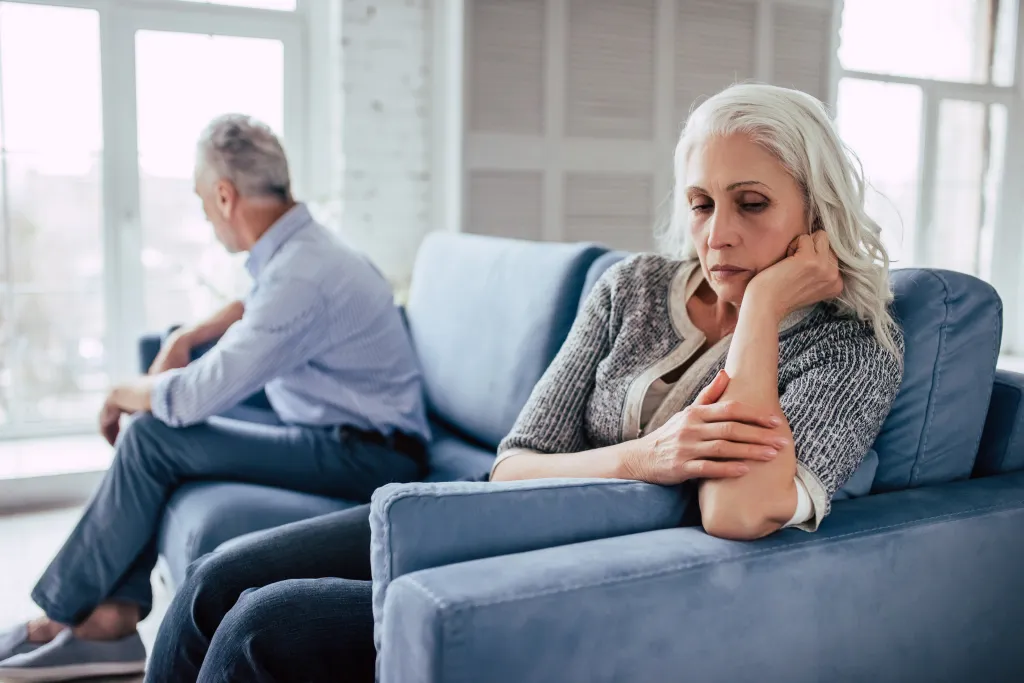 Upset senior couple on a sofa facing away from each other.