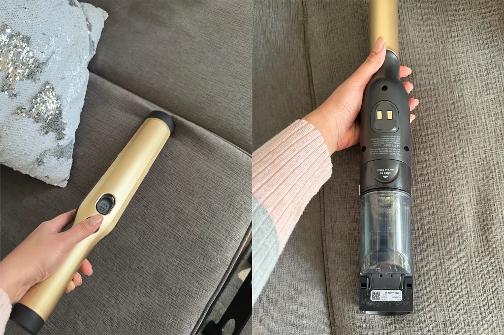 A person using a gold-colored Shark vacuum cleaner on a gray sofa.