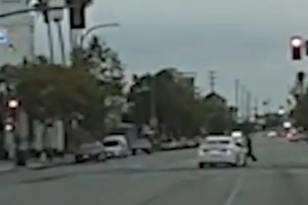 A white car swerving to hit pedestrians in the street.
